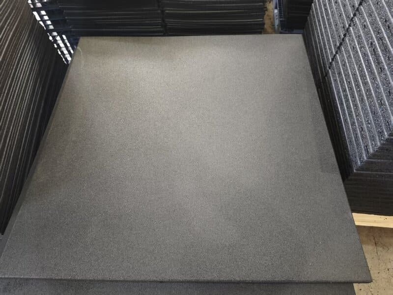 alt text: Close up of impact testing machine on rubber gym tile in a laboratory setting